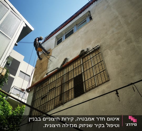 אדם מטפס על קיר בניין עם חבלים